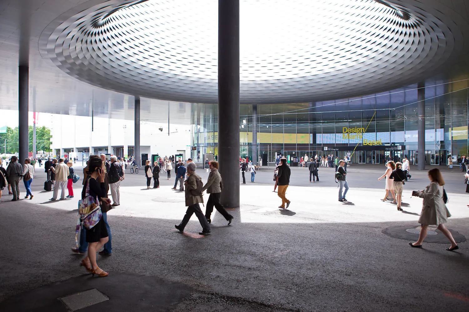 Visitors crossing the Messe Basel courtyard beneath the great circular canopy.