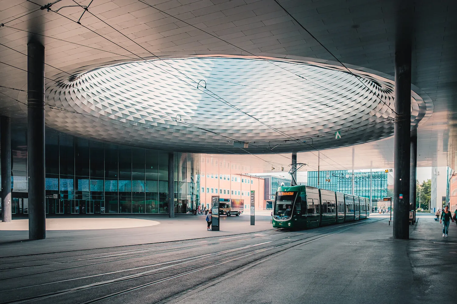 A tram passing beneath the great latticed canopy of Messe Basel.