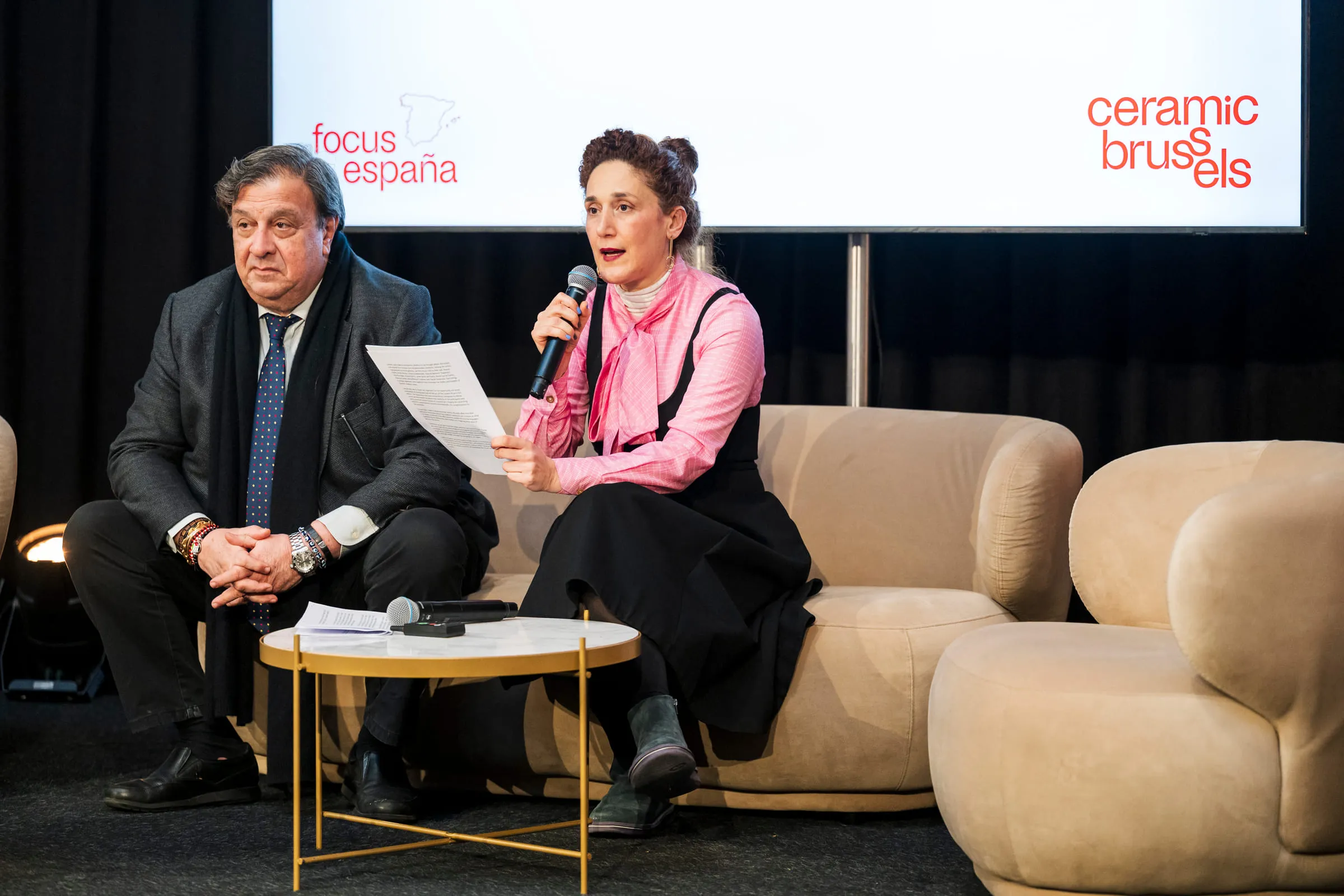 Two speakers on stage in front of a screen reading “focus españa”.